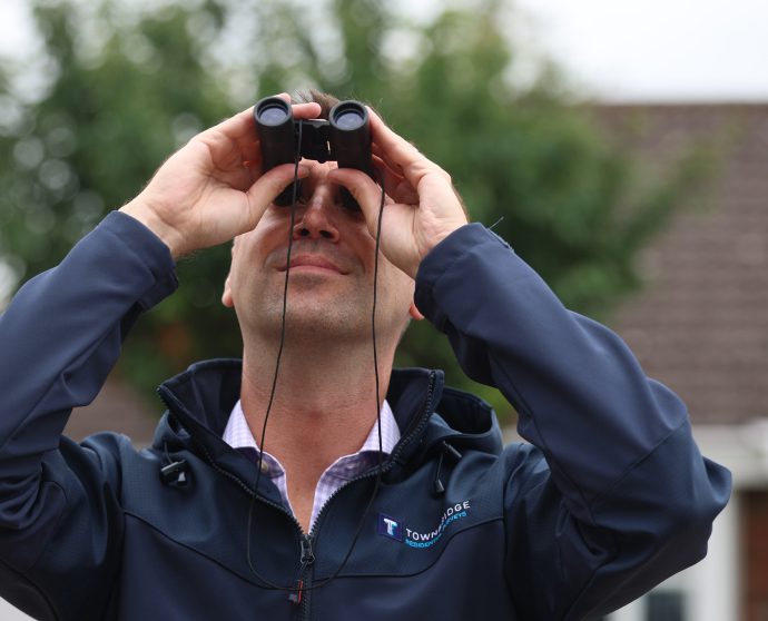 A man looking through binoculars, scanning the landscape ahead.